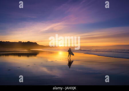 Surfer am Strand bei Sonnenuntergang Stockfoto