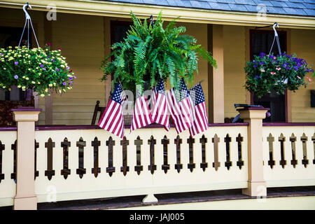 Amerikanische Flaggen auf einer Veranda mit hängenden Pflanzen, Cape May County, New Jersey, US-Flagge 2017, Amerika hängende Körbe Pflanzen Stockfoto