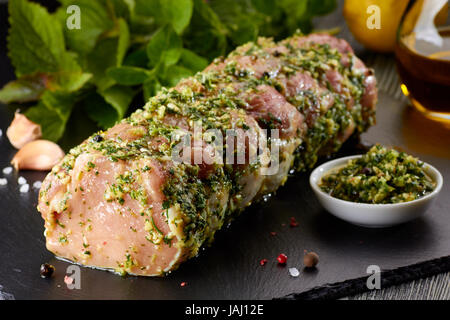 Rohe Schweinelende mit Gewürzen auf schwarzen Steinplatte. Fertig zum Backen Stockfoto