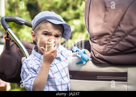 Großer Bruder beobachten und bewachen Bruder junior in Perambulator beim gehen im Sommerpark und Essen ein Eis als Konzept für die Familienbande Stockfoto