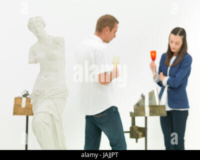 Frau und Mann, die Prüfung der zeitgenössischen Skulptur hinter eine Replik der Venus von Milo Statue in einem museum Stockfoto