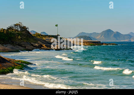 Blick auf des Teufels Strand und das Copacabana Fort mit der brasilianischen Flagge und den Hügeln der Stadt Niteroi im Hintergrund Stockfoto