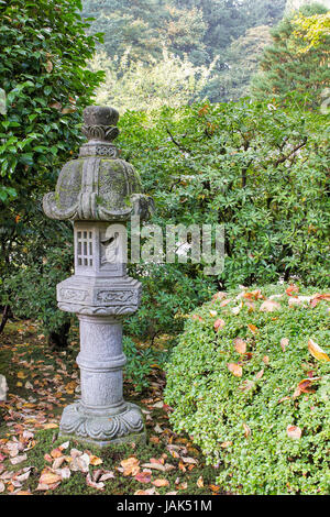 Japanische Stein Laterne im Garten mit Pflanzen und Sträuchern in Herbstsaison Stockfoto