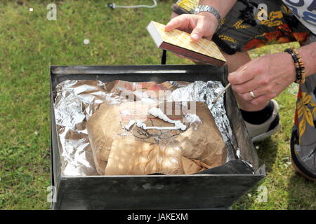 Beginnend einen Grill mit einer Tasche von instant Beleuchtung Lumpwood Kohle für das Kochen im freien Stockfoto