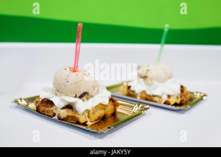 Zwei köstliche Desserts mit Eis serviert auf Metall Tabletts mit bunten Plastik Löffel gekrönt eingebettet in der oberen Stockfoto