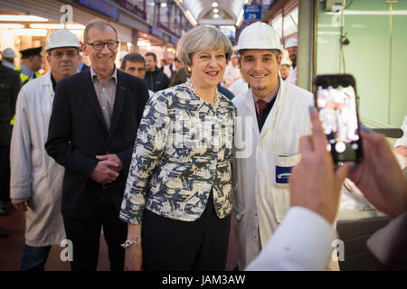 Premierminister Theresa May posiert für ein Foto während eines Besuchs in Smithfield Market in der City of London mit ihrem Ehemann Philip (links, mit Brille) am letzten Tag der Wahlkampf für die Parlamentswahlen am Donnerstag. Stockfoto