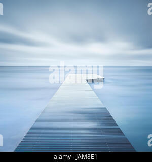 Hölzerne Pier oder Steg, Felsen und ruhige See. Langzeitbelichtung Stockfoto
