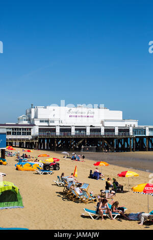 Gesamtansicht der Sandown Pier auf der Isle Of Wight mit dem belebten Strand im Vordergrund an einem sonnigen Sommertag. Stockfoto