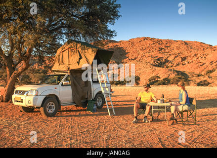 Paar Camping in der Wüste Abendessen. orange Sonnenuntergang sonnenaufgang Licht. Stockfoto