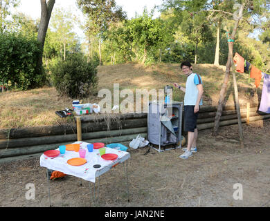 Junge Camper bereitet Abendessen auf dem Campingplatz des Ortes im Sommer Stockfoto