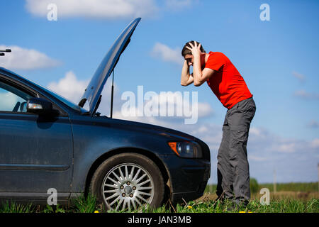 Frustriert Mann am Auto mit offener Haube tagsüber unterwegs Stockfoto