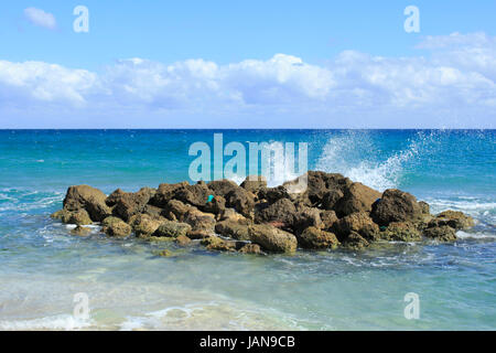 An einem sonnigen Tag Wellen spritzen auf Felsen auf Deerfield Beach, Florida, eine schöne Szene und unvergesslichen wegen seiner Schönheit, Ungewöhnlichkeit und Energie mit seinen blauen Tuch gewaschen an Land. Stockfoto