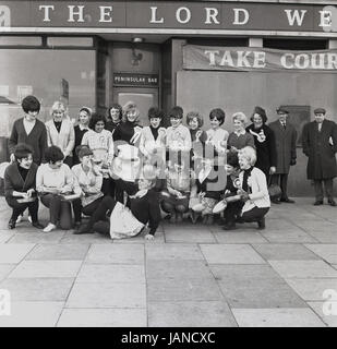 1965, historische, posieren für ein Foto vor The Lord Wellington Schambein Haus im Old Kent Road, Peckham, London in ihre Schürzen und mit ihren Pfannen vor dem jährlichen Faschingsdienstag Pfannkuchen Rennen weibliche Teilnehmern. Stockfoto