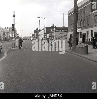 1965, historische, Bild zeigt eine Reihe von Damen der Old Kent Road, Peckham, London, vorbei an dem Astoria-Theater, mit Pfannen und Schürzen in der traditionellen Fastnacht Pfannkuchen Rennen liefen. Stockfoto