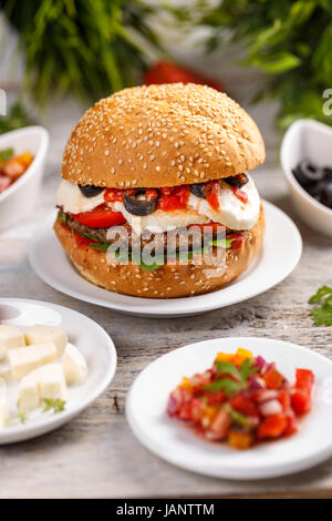 Leckere Burger mit Rindfleisch Patty serviert mit Tomatensalat Stockfoto