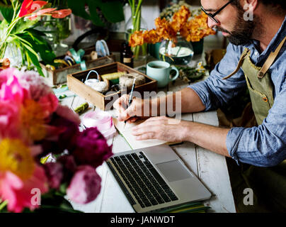 Mann Blume Shop Besitzer schreiben Hinweis auf dem Tisch Stockfoto