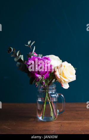 Frische Blumen und Vase in einer Vase auf Holztisch Stockfoto