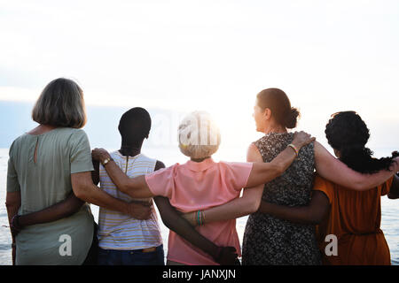 Rückansicht der unterschiedlichen Frauen in Führungspositionen stehen zusammen am Strand Stockfoto