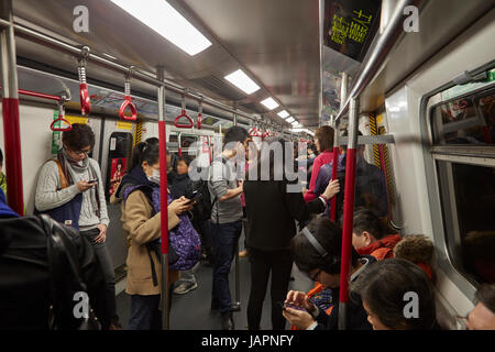 Passagiere auf ihren Smartphones auf MTR u-Bahn System, Hong Kong, China Stockfoto