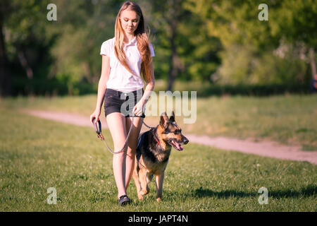 Teenager-Mädchen in weißen Hemd mit ihrem Schäferhund-Hund im Park spazieren Stockfoto