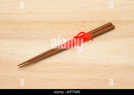 Japanische Essstäbchen aus Holz verpackt in rotem Papier und roten Seil auf weißem Hintergrund. Stockfoto