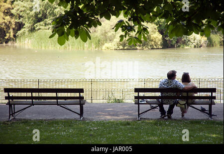 Paar sitzt auf schattigen Bank am Battersea Park im Sommer - London-UK Stockfoto