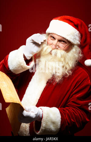 Porträt von happy Santa Claus Weihnachtsbrief in den Händen hält und Blick in die Kamera Stockfoto