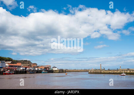 Blauer Himmel mit Cumulus-Wolken an einem sonnigen Sommertag am Hafen von Whitby, mit Angelboote/Fischerboote vertäut am Kai Fisch und fernen Leuchttürmen Stockfoto