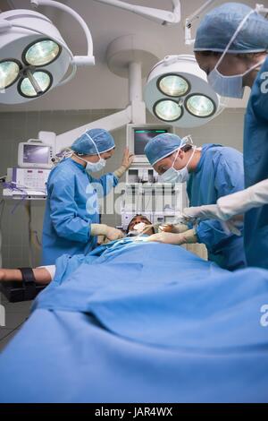 Gruppe von Chirurgen arbeiten auf eine unbewusste männliche Patienten Stockfoto