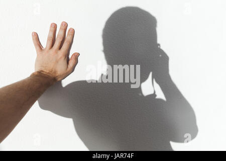 Mann berühren seinen Schatten auf die weiße Wand und nehmen Foto Stockfoto