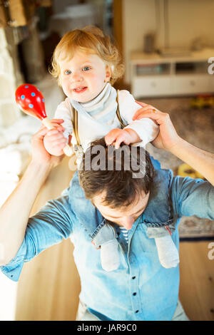 Junger Vater zu Hause geben seinen kleinen Sohn Huckepack. Stockfoto