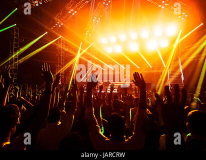 Foto von jungen Menschen, die Spaß am Rock-Konzert, aktiven Lebensstil, Fans applaudieren berühmte Musikgruppe, Nachtleben, dj auf der Bühne im Club, auf der Tanzfläche, Nacht Perfomance tanzende Menge Stockfoto