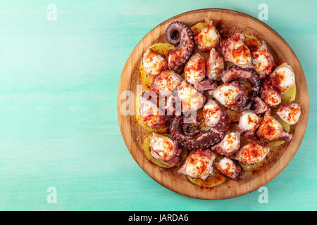 Eine obenliegende Foto von Pulpo a la Gallega, eine Krake mit gekochten Kartoffeln, typisch spanisches Gericht, auf einer traditionellen hölzernen Platte eine Krickente Hintergrund Witz Stockfoto