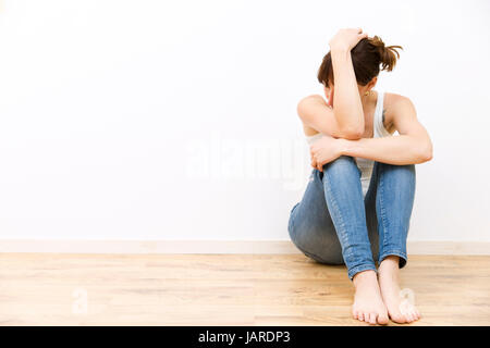 Depressiv, traurig, junge Frau am Boden hielt ihren Kopf Stockfoto