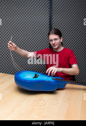 Entfernen die alten Saiten eine Elektro-akustische Gitarre (Serie mit dem gleichen Modell verfügbar) Stockfoto