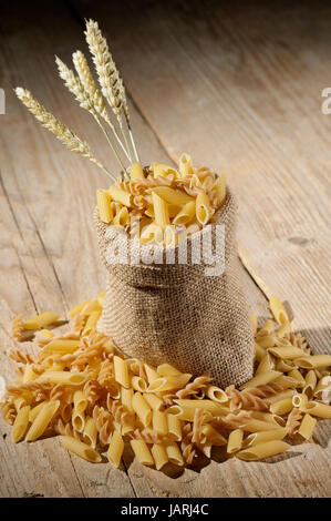 Jute-Tasche mit unterschiedlichsten Teigwaren auf Holztisch Stockfoto