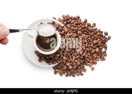 strömenden Zucker mit einem Teelöffel auf Tasse Kaffee auf weißem Hintergrund Stockfoto