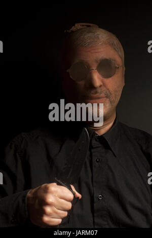 Kriminelle Mann mit Messer tragen Strumpf über den Kopf auf schwarzem Hintergrund Stockfoto