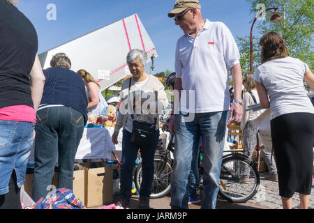 Menschen, die an einem sonnigen Sommertag Kleidung und Haushaltsartikel auf einem Markt im Freien oder einem Autoschuhverkauf in Schweden suchen. Stockfoto