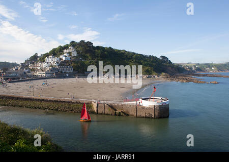 Ein Schlauchboot mit einem roten Segel Köpfe heraus zum Meer vorbei an den Banjo-Pier in Looe, Cornwall mit der Stadt und der Strand im Hintergrund Stockfoto