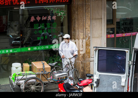 Lieferung Mann mit Fahrrad und Karren, Nanjing Road (East), Shanghai, China Stockfoto