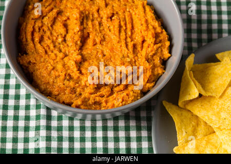 Schüssel mit hausgemachten Karotten Hummus, bereit für das Essen mit Tortilla-Chips auf der Seite. Stockfoto