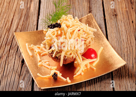 Ofenkartoffel mit geriebenen Cheddar-Käse bestreut Stockfoto