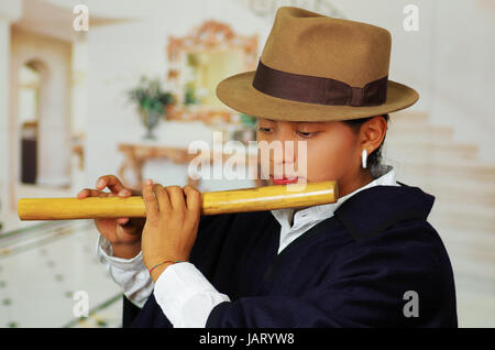 Porträt von hübschen jungen indigenen Mann aus Otavalo, Ecuador, Quena Flötenspiel hautnah Stockfoto