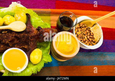 Ecuadorianische Traditionsgericht, gegrillte Meerschweinchen verteilt auf grüne Platte, Kartoffeln, Tostados und Zitronen auf der Seite, von oben gesehen. Stockfoto