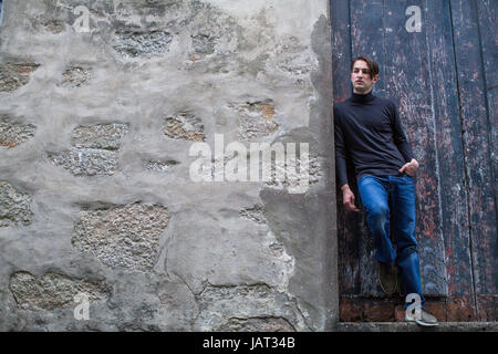 Hübscher junger Mann stehend schiefen an der Wand. Stockfoto