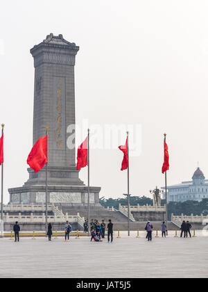 Peking, CHINA - 19. März 2017: Menschen und rote Fahnen in der Nähe von Denkmal für die Helden des Volkes auf dem Tiananmen-Platz im Frühjahr. Tiananmen-Platz ist von zentraler Bedeutung Stockfoto