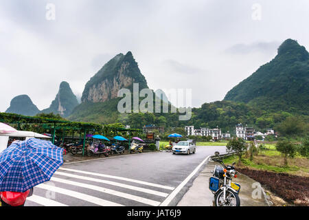 YANGSHUO, CHINA - 29. März 2017: Auto und Roller Parkplätze in der Nähe von Tor zum Dorf in Yangshuo County. Stadt ist Resort-Destination für inländische und fo Stockfoto