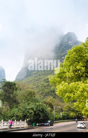 YANGSHUO, CHINA - 29. März 2017: Menschen unterwegs auf Drachenbrücke (Gong Nong, Gongnong Brücke) über Yulong River in der Nähe von bewachsenen Karstberge in Yan Stockfoto