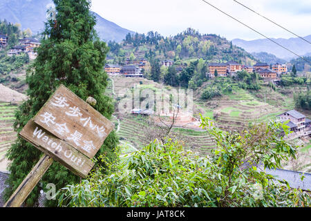 Reisen Sie nach China - oben Blick auf das Dorf Dazhai auf grünen Hügeln im Bereich Longsheng Reisterrassen (Longji Reisterrassen) im Frühjahr Stockfoto